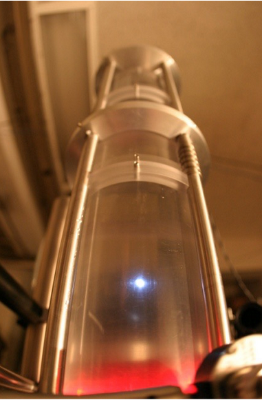 Burbuja de sonoluminiscencia brillando en el centro de un vaso